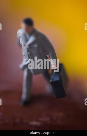 Miniaturfigur eines Mannes, der mit Koffer geht. Stockfoto
