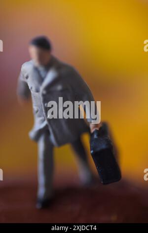 Miniaturfigur eines Mannes, der mit Koffer geht. Stockfoto