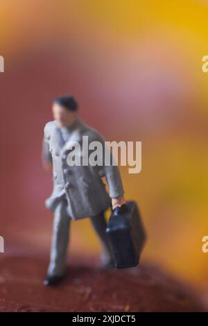 Miniaturfigur eines Mannes, der mit Koffer geht. Stockfoto