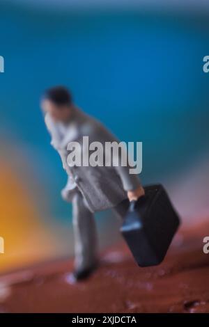 Miniaturfigur eines Mannes, der mit Koffer geht. Stockfoto