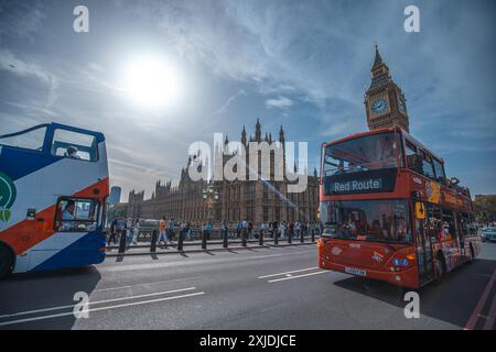 London, UK - 09. Oktober 2023 : zwei Doppeldeckerbusse fahren auf einer Londoner Straße vorbei an Big Ben und den Houses of Parliament unter hellblauem Himmel. Stockfoto