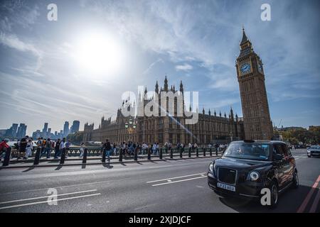 London, UK - 09. Oktober 2023 : Ein schwarzes Londoner Taxi fährt auf einer Straße in London, Großbritannien. Der berühmte Big Ben Turm ist im Hintergrund zu sehen, al Stockfoto