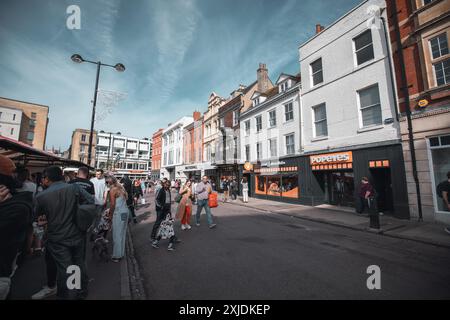 Cambridge, UK - 8. Oktober 2023 : Eine geschäftige Straße in Cambridge, Großbritannien, wo Menschen an Geschäften und einem Markt vorbeilaufen. Stockfoto