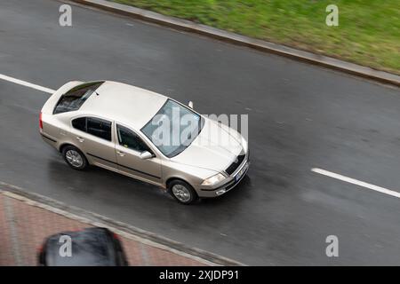 OSTRAVA, TSCHECHISCHE REPUBLIK - 23. MÄRZ 2024: Hellbraunes Skoda Octavia Liftback-Auto im Regen mit Bewegungsunschärfe-Effekt, rostiger Kotflügel Stockfoto