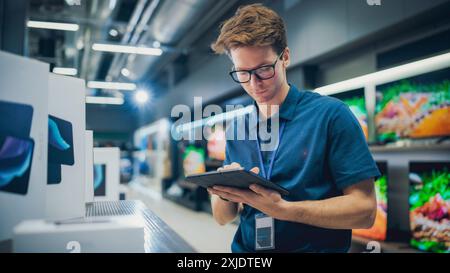 Porträt des Vertriebsmitarbeiters im Home Electronics Store mit Tablet-Computer für Online-Workflow. Junger Mitarbeiter verwaltet Lagerbestand, Produktverfügbarkeit und Kundenbestellungen über das Internet Stockfoto