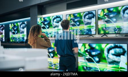 Weibliche Kundenbindung ein Gespräch mit einem Fachberater für Elektronik im Einzelhandel. Frau sucht intelligentes, internetinternetinternetinternetinternetinternetinternes Kunde erkundet erweiterte Fernsehoptionen im modernen Einzelhandel Stockfoto