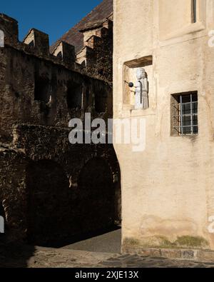 Sehr alte Gebäude mit einer Statue im Herzen eines Dorfes im Sonnenlicht Stockfoto