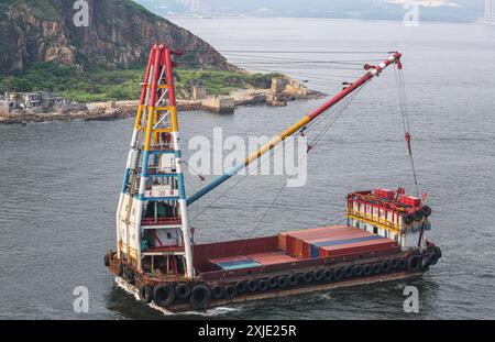 Hongkong, China: Krankahn mit Containern, die von einem größeren Containerschiff entladen werden, internationale Schifffahrtsindustrie, schwimmende Kräne Stockfoto