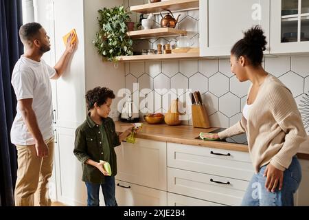 Ein afroamerikanischer Mann und eine afroamerikanische Frau putzen gemeinsam die Küche, zeigen Liebe und Teamarbeit, mit dem Sohn. Stockfoto