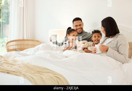 Fröhliche Familie, morgens und entspannen Sie mit Kindern im Bett für einen Kaffee, beginnen Sie oder verbinden Sie sich zu Hause. Mutter, Vater und Kinder lachen vor einem Lächeln für den Urlaub Stockfoto