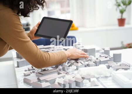 Architektin, die ein Tablet am Bibliothekstisch benutzt, während sie ein Stadttraining erstellt Stockfoto