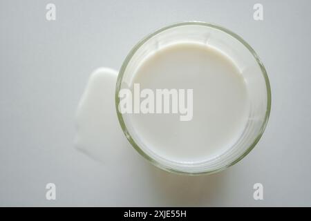 Milch im Glas und verschüttete Milch von oben auf weißem Hintergrund Stockfoto