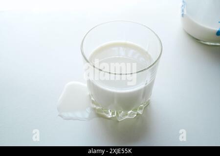 Milch im Glas und Milchflasche auf weißem Tisch Stockfoto