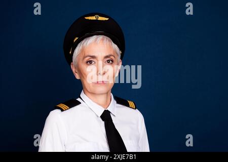 Foto-Porträt der attraktiven älteren Dame Passagier Flugzeug Kapitän Blick Kamera gekleidet Piloten Uniform isoliert auf dunkelblauem Farbhintergrund Stockfoto