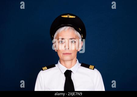 Foto-Porträt der hübschen pensionierten weiblichen professionellen Flugzeugpiloten tragen Pilotenuniform isoliert auf dunkelblauem Hintergrund Stockfoto