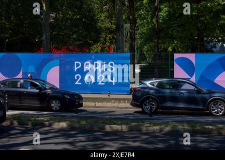 Ein Banner für die Olympischen Spiele 2024 in Paris hängt am Straßenrand im Zentrum von Paris. Vorbeifahrende Autos. Stockfoto