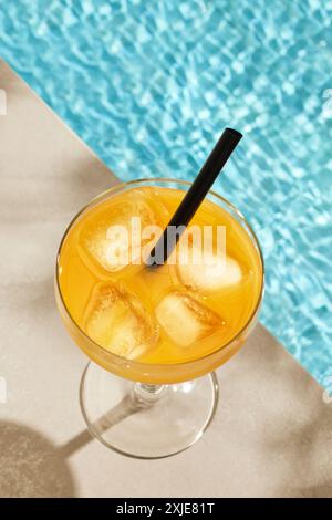 Ein Glas Eisorange am Rand des Swimmingpools an sonnigen Tagen Stockfoto