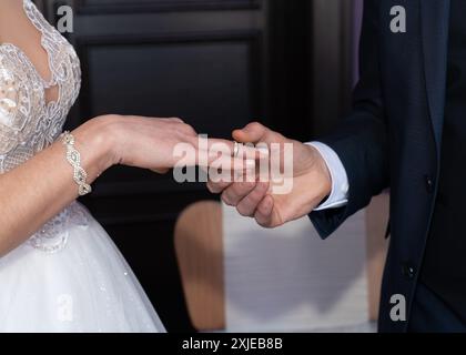 Der Bräutigam legt der Braut einen Ehering an den Finger. Ohne Gesicht Stockfoto