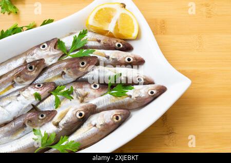 Frische, ungekochte Schellfisch-Fische in Keramikschale auf dem Tisch, roher Wittling-Fisch-Konzept Stockfoto