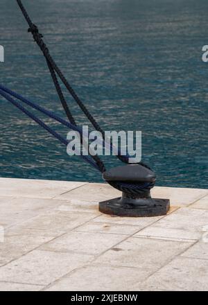 Ankerseile am Pier vor dem Hintergrund des blauen Meeres und des weißen Piers. Nahaufnahme Stockfoto