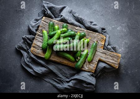 Frische, reife Bio-Gurken in Schüssel oder Korb auf rustikalem Tisch, nicht mariniertes Gemüse, Cornichon Stockfoto