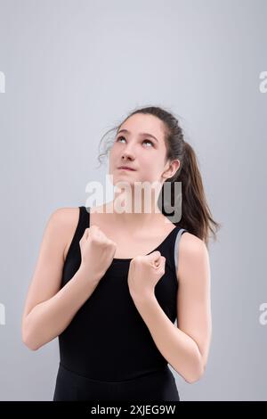 Die junge Frau blickt hoffnungsvoll auf und ballt ihre Fäuste mit Entschlossenheit. Sie wartet darauf, dass etwas Wichtiges passiert Stockfoto