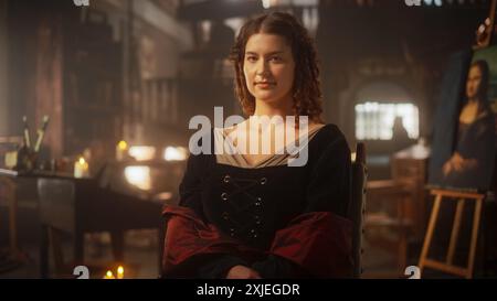 Schöne junge Frau posiert für ein Porträt, sieht die Kamera an und lächelt in einem Antiquitätenstudio. Historische Figur, inspiriert von da Vincis Gemälde, die Mona Lisa, in der Darstellung der Renaissance Stockfoto