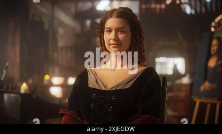 Renaissancezeit-Darstellung: Schöne junge Frau posiert für ein Porträt, schaut auf die Kamera und lächelt in einem Antiquitätenstudio. Historische Figur, inspiriert da Vincis Gemälde, die Mona Lisa Stockfoto