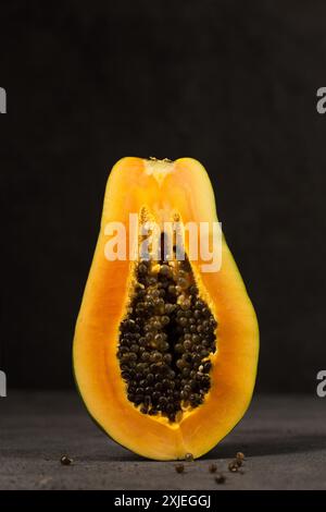 Eine halbe reife Papaya steht direkt vor einem dunklen Hintergrund Stockfoto