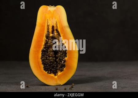 Eine halbe reife Papaya steht direkt vor einem dunklen Hintergrund Stockfoto