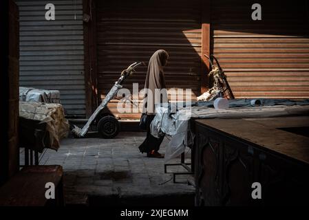 Kairo, Ägypten. 1. Juli 2024 eine ägyptische muslimische Frau spaziert durch die Kopfsteinpflasterstraßen eines geschlossenen Marktes in der Nähe der Al Ahzar Moschee in Midan Hussein auf der Insel Stockfoto