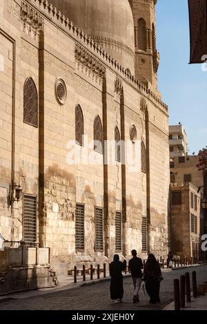 Einheimische Touristen gehen an einem der vielen restaurierten Denkmäler entlang der Sharia Al Muizz Li DIN Allah in der Nähe des Khan El Khalili Basars im historischen Kairo, Ägypten vorbei. Stockfoto