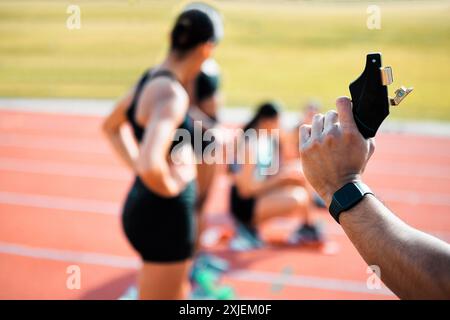 Hand-, Renn- und Feuerwehrpistole zum Laufen oder Training mit Athleten auf der Strecke. Starterpistole, Gruppe oder Frauen auf dem Stadionfeld, um sich darauf vorzubereiten Stockfoto