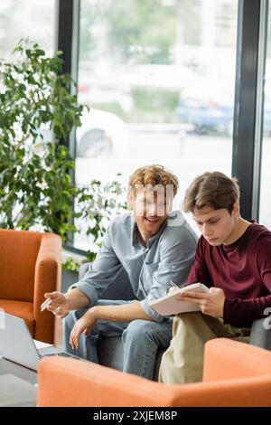 Zwei Männer sitzen auf einer Couch und konzentrieren sich auf einen Laptop-Bildschirm. Stockfoto