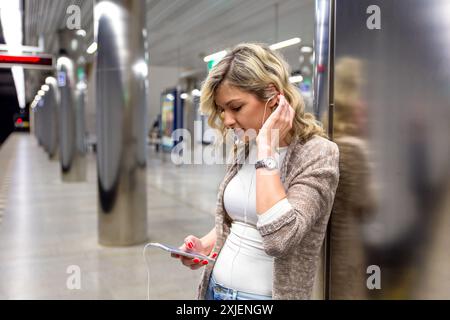 Junge Frau mit Koffer warten Zug in der U-Bahn Station. Stockfoto
