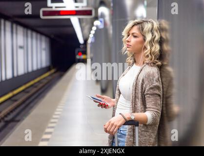 Junge Frau mit Koffer warten Zug in der U-Bahn Station. Stockfoto