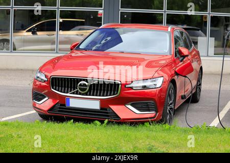 Rotes Volvo V60 (II) AWD 2024 Hybrid-Elektroauto mit Batterieladegerät im Händlerbetrieb in Salo, Finnland. Juli 2024. Stockfoto