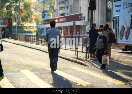 Hongkong, China - 3. Januar 2024 : Ein Mann geht über einen Quersteg in Zentral-Hongkong. Der Fußweg ist mit gelben Linien markiert und es gibt SHA Stockfoto