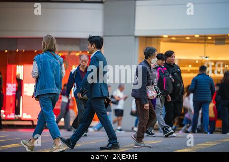Hongkong, China - 03. Januar 2024 : Menschen gehen über eine Straße in Hongkong, China. Einige tragen Gesichtsmasken, während andere im Hintergrund unscharf sind Stockfoto
