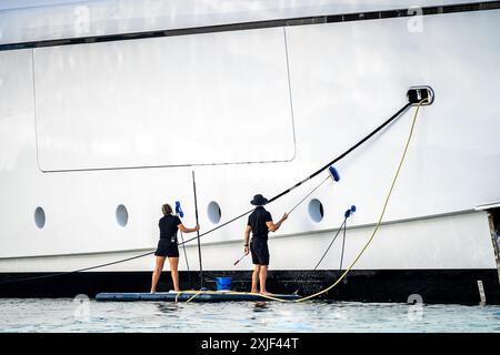 Super Yachtbesatzung, zwei Deckhände, männlich und weiblich, die Seite eines weißen Megas am Dock im Englischen Hafen, einer berühmten karibikinsel Antigua KN, reinigen Stockfoto