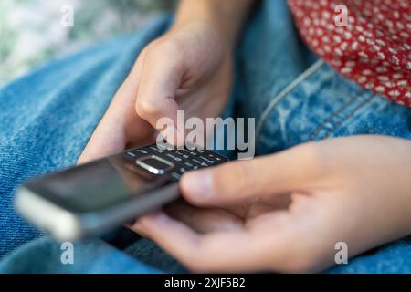 Nahaufnahme Eines Teenager-Mädchens, Das Basic Dumb Push Button Handy Für Nachrichten Ohne Online-Verbindung Verwendet Stockfoto