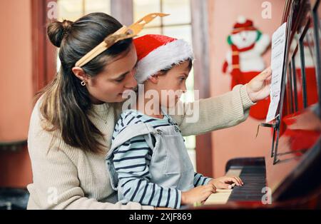 Mutter, Sohn und Klavier zu Hause für Weihnachtslied mit Bindung, Lernen und Feiertagsfeier. Mutter, Junge und Instrument oder Tastatur für Stockfoto