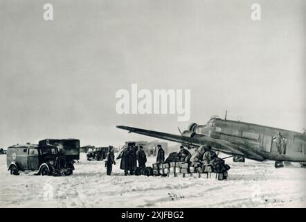 Ein Foto zeigt, wie Vorräte von einem Junkers Ju 52 während der Operation Barbarossa im Jahr 1941 entladen wurden. Das Flugzeug landete nahe der Front, um Waffen, Munition und Proviant an ein Sturmbataillon zu liefern. Krankenwagen werden gesehen, wie sie verwundete Soldaten zur Evakuierung in das Flugzeug schleppten, was die logistischen und medizinischen Bemühungen unterstreicht, während die deutschen Truppen an der Ostfront gegen die sowjetischen Truppen vorrückten. Stockfoto