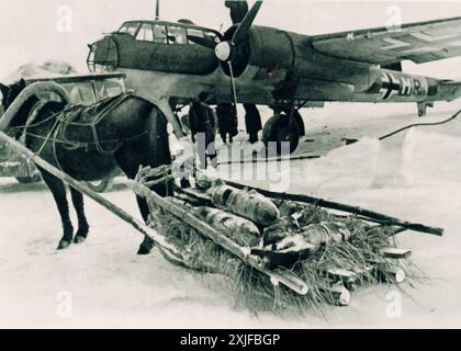 Ein Foto zeigt Pferde, die während der Operation Barbarossa 1941 Bomben auf einem Schlitten zu einem Dornier Do 17 transportieren. Die deutschen Streitkräfte verwendeten aufgrund der harten Schneelage an der Ostfront traditionelle Transportmethoden. Stockfoto