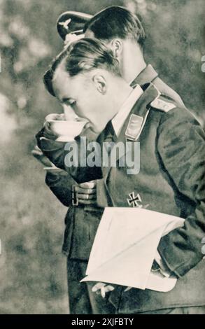 Ein Foto zeigt Lieutenant G., der eine warme Erfrischung aus einer Tasse trinkt. Dieses Bild wurde 1941 während der Operation Barbarossa aufgenommen und hält einen kurzen Moment der Ruhe für den Luftwaffenoffizier während eines Briefings über die Ostfront fest. Stockfoto