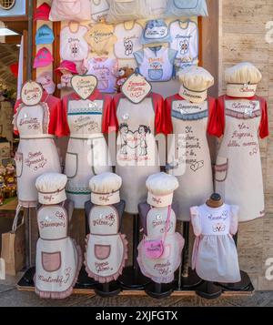 ALGHERO, ITALIEN - 4. JULI 2024: Lokale Modelle traditioneller und typischer sardischer Kochkostüme werden vor einem Souvenirladen auf einer Straße zum Verkauf angeboten Stockfoto