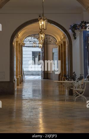 München, Deutschland - 21. Dezember 2023 - perspektivischer Blick auf den Bogengang mit antiker Laterne, die von der Decke hängt, im antiken Gebäude. Designelemente von Stockfoto