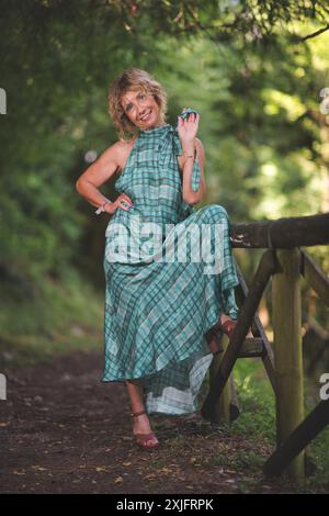 Eine glückliche Frau in der Nähe eines hölzernen Zauns im Wald Stockfoto