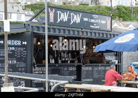 Zwei Leute essen draußen im Dan-Dan The Lobster man Portleven Harbour Cornwall UK Stockfoto