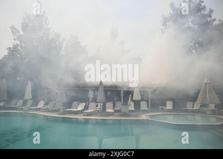 Thessaloniki, Griechenland. Juli 2024. Rauch im Poolbereich, während ein Bürstenfeuer neben einem Hotel im Vorort von Trilofos in der Nähe der Stadt Thessaloniki brennt. (Kreditbild: © Giannis Papanikos/ZUMA Press Wire) NUR REDAKTIONELLE VERWENDUNG! Nicht für kommerzielle ZWECKE! Stockfoto